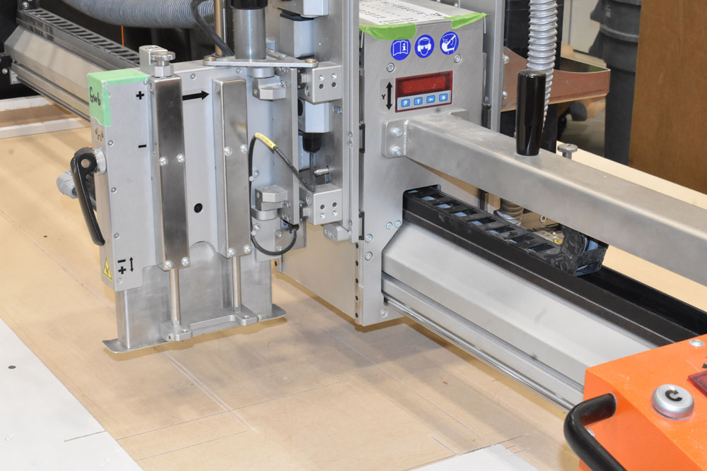 Plywood cutting tool positioned over a sheet on the cutting table